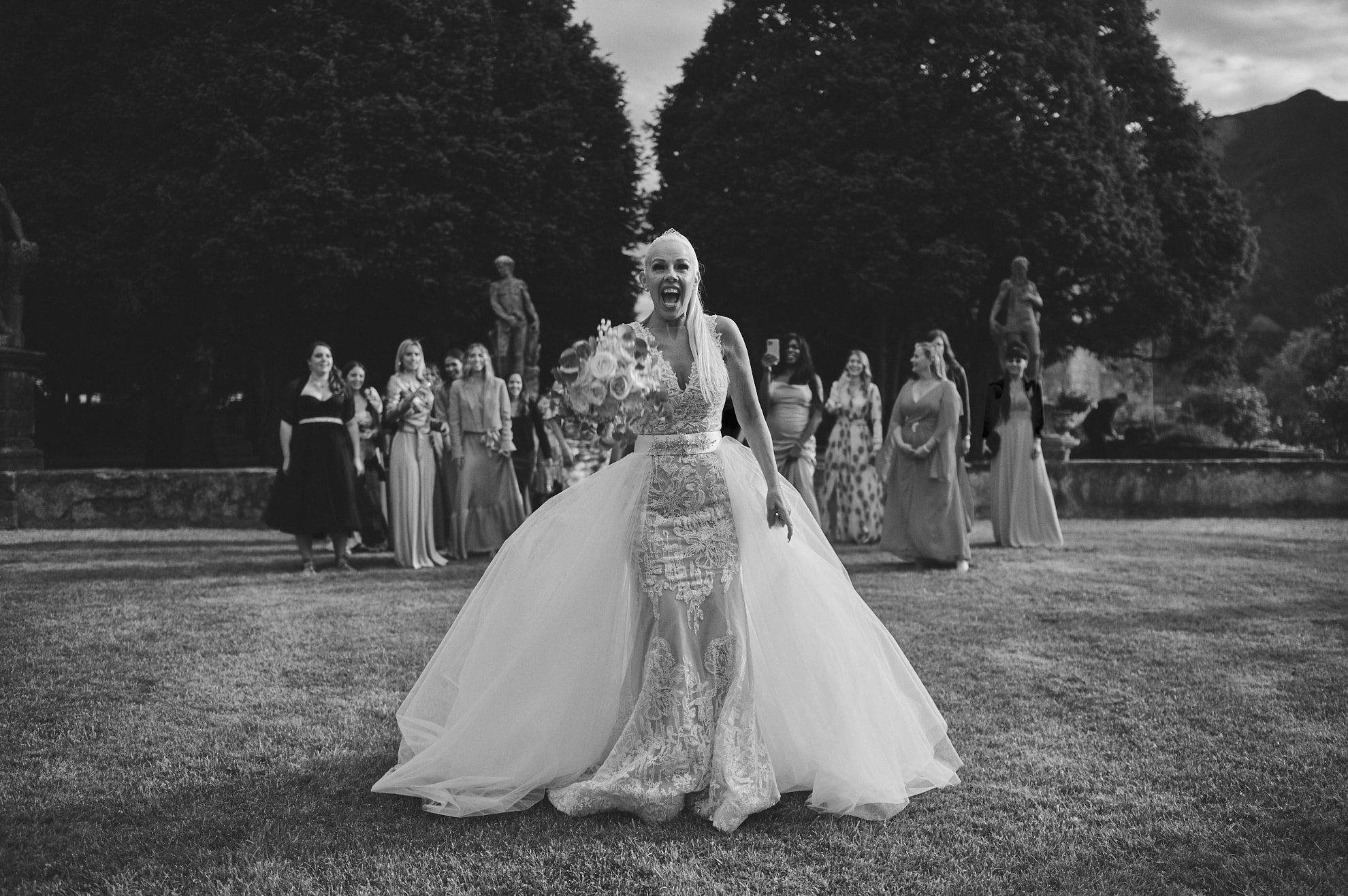 foto sposa in bianco e nero mentre sta per fare il lancio del bouquet a Villa Bortolazzi Trento